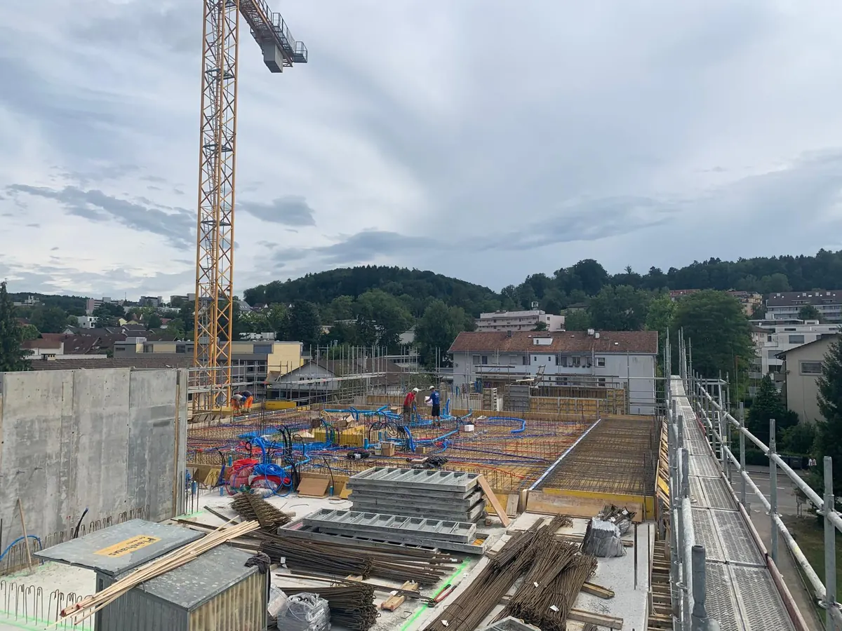 Blick über eine eingeschalte Geschossdecke mit Baukran und bereitgelegten Bewehrungseisen