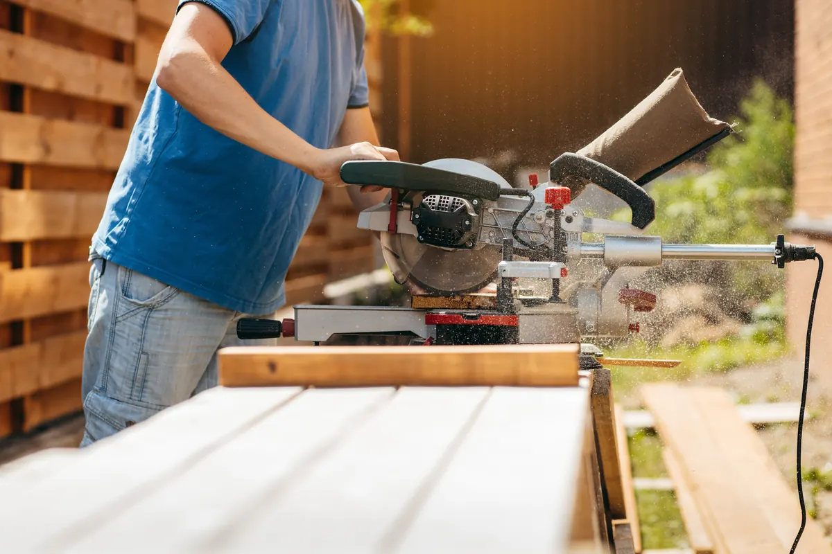 Handwerker sägt Holzlatten für eine moderne Sichtschutzwand zu